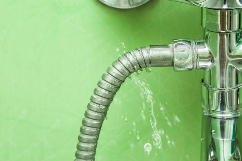 Your Complete Guide to Finding and Fixing Water Leaks. Damaged leaking water tap hose in the bathroom of house.