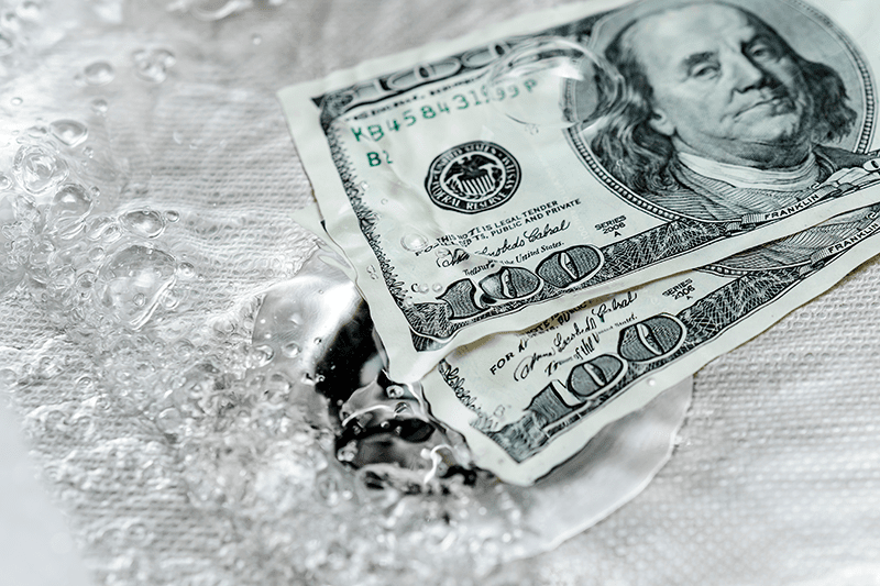 Money sits in a sink of water. 5 Plumbing Problems Costing You Money.