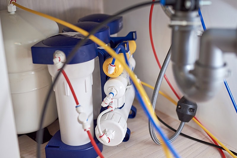 What Is Reverse Osmosis? Photo of a water system installed underneath a kitchen sink.