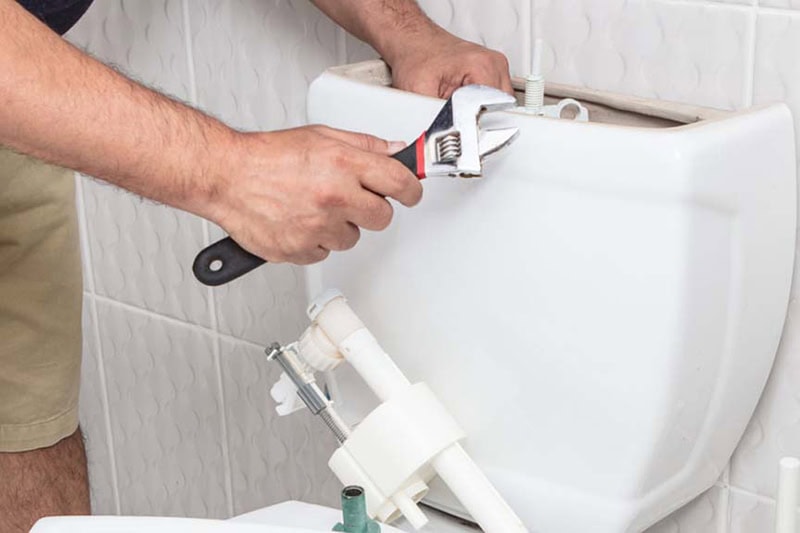 Plumber performing maintenance on toilet.