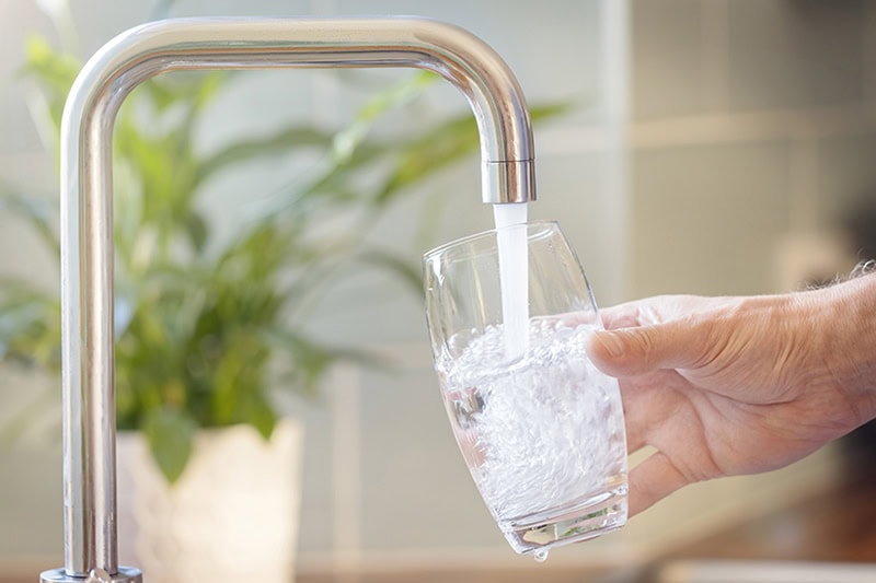 Deduct Meters: Saving Money in California. Filling up a glass with drinking water from kitchen tap.